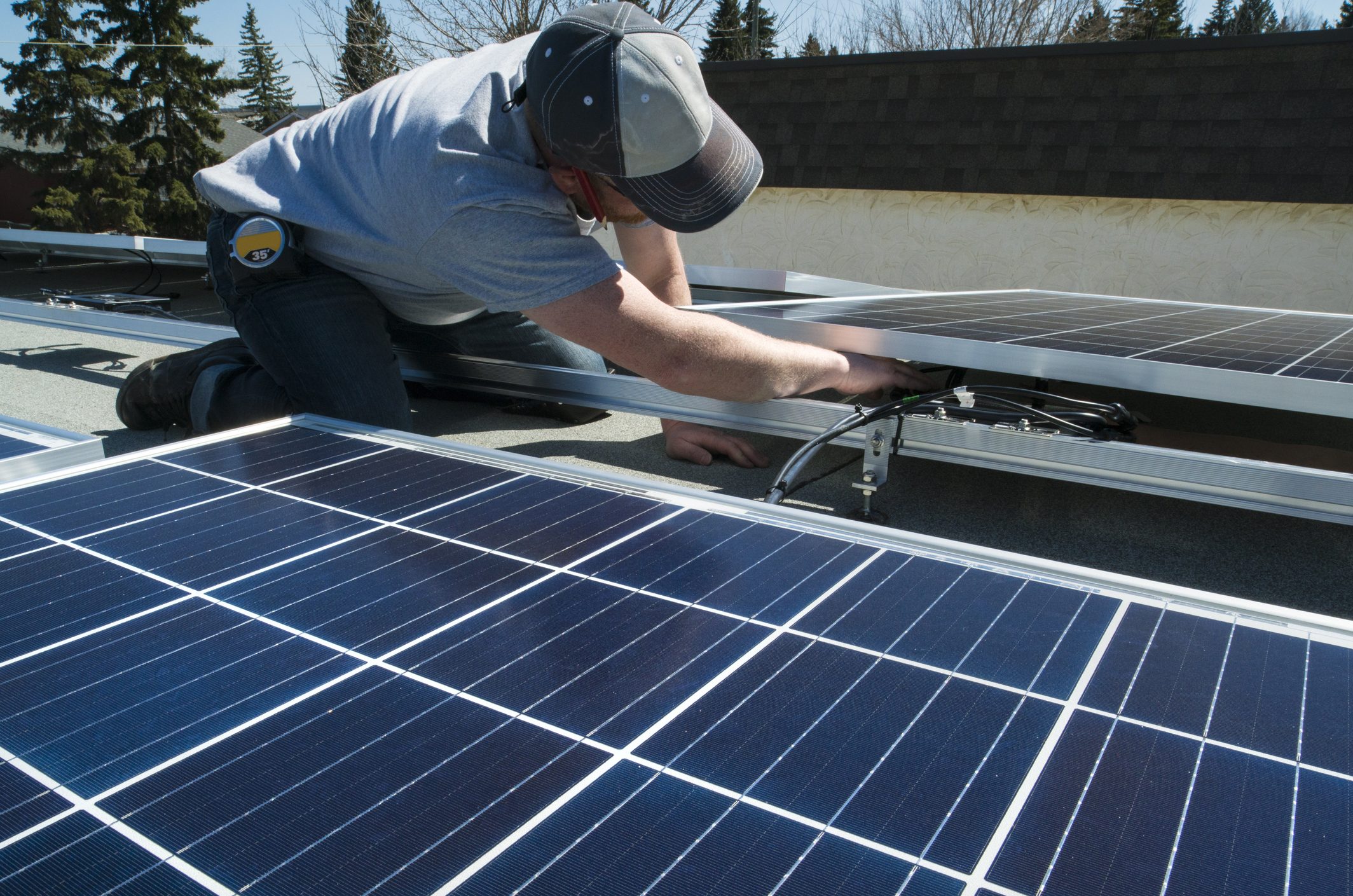 Ouvrier pose de panneaux solaires photovoltaïques sur toit plat Energreen